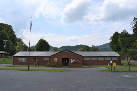 A brick building with an Erwin National Fish Hatchery sign and parking lot pictured on a sunny day