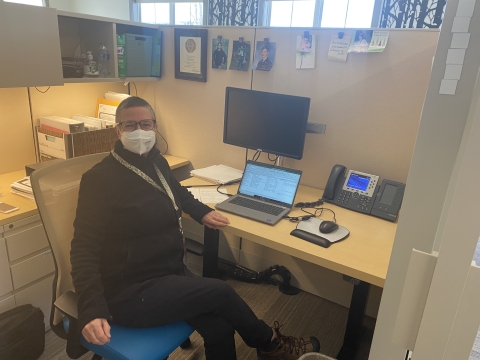 a woman wearing a face mask sitting in a cubicle