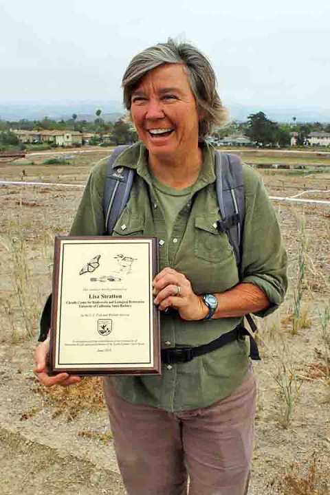 A woman smiling and holding an award 