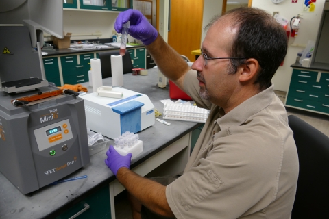 Man in lab holds up vile.