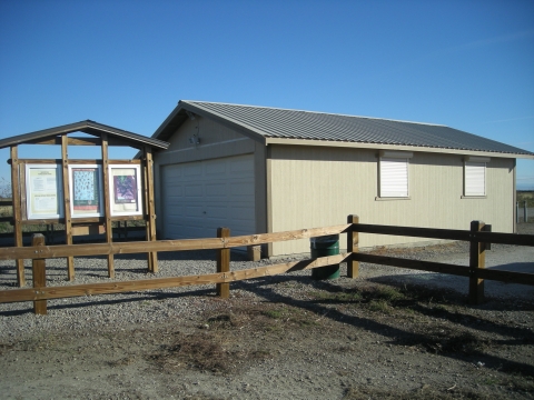 photo of off white building with kiosk to the left and brown fence in foreground