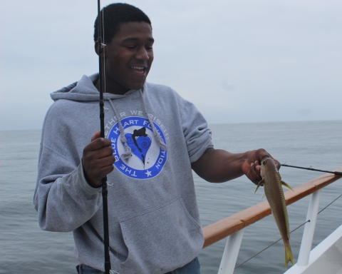 Young man holds white fish.