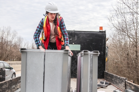 Person standing in the back of a flatbed truck examining artificial bat roosts