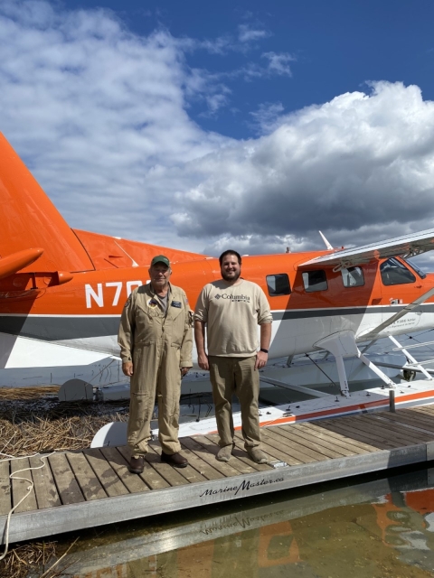 2 people stand in front of an airplane