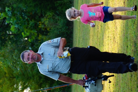 Michael Johnson carries fishing poles while walking with his granddaughter.