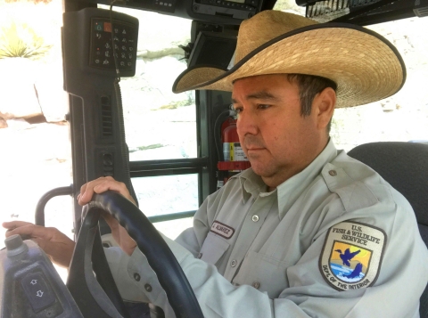 A man in a hat and a U.S. Fish and Wildlife Service uniform sitting in the cab of a vehicle