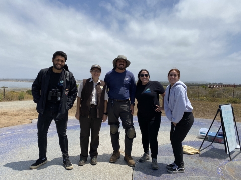 Five individuals from an environmental education program stand side by side and smile for a photo.