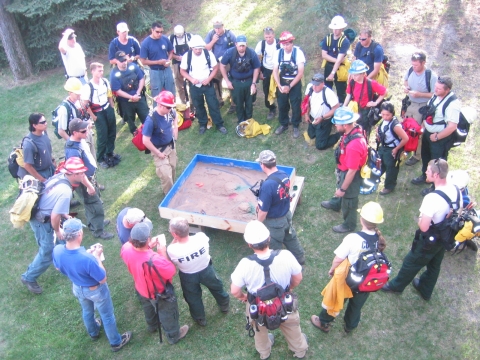 group stands around what looks like sandbox