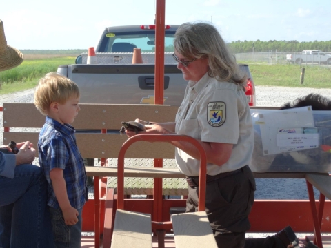 a woman wearing a service uniform shows a turtle to a small boy