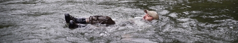 Man floating down a river on his back without a floatation device.