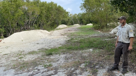 Man standing next to field with sandy mounds