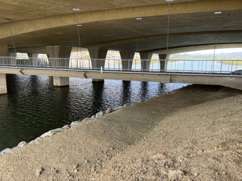 a walking bridge hangs above a dirt path