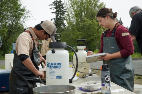 Service intern, Hannah Ferwerda, and technician Marc Solano collecting at a table. fish data and stomach samples and data 