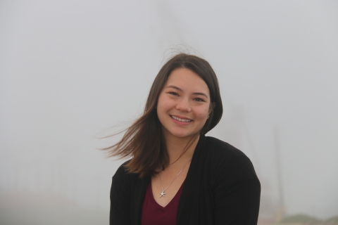 A woman standing in front of a foggy beach