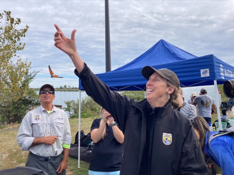 Woman wearing jacket with U.S. Fish and Wildlife Service logo releasing a butterfly