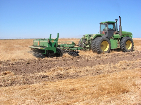 Refuge staff operating heavy equipment in a farm field.