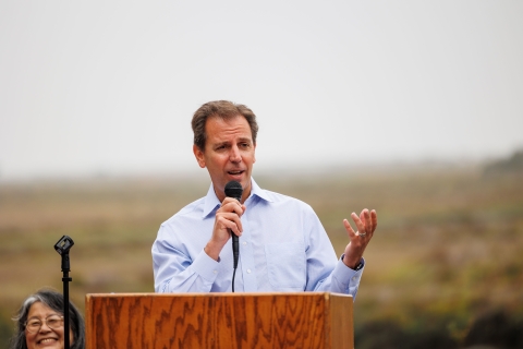 A man stands at a podium speaking into a microphone