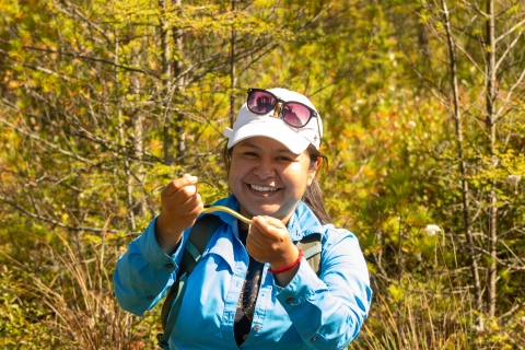 A biologist holds a green snake