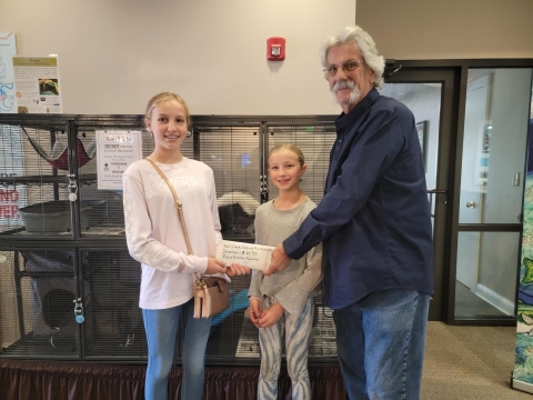 young girls handing an envelope to a volunteer 