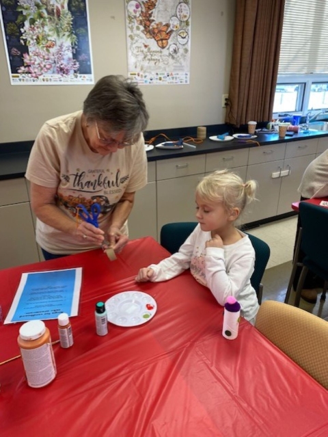 Woman helping child make a craft