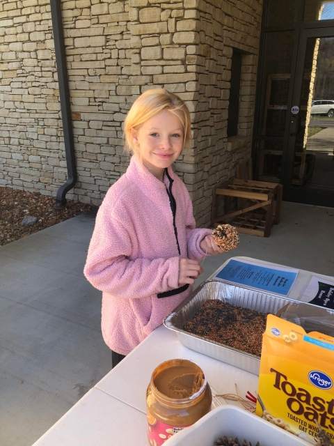 Girl holding pinecone birdfeeder