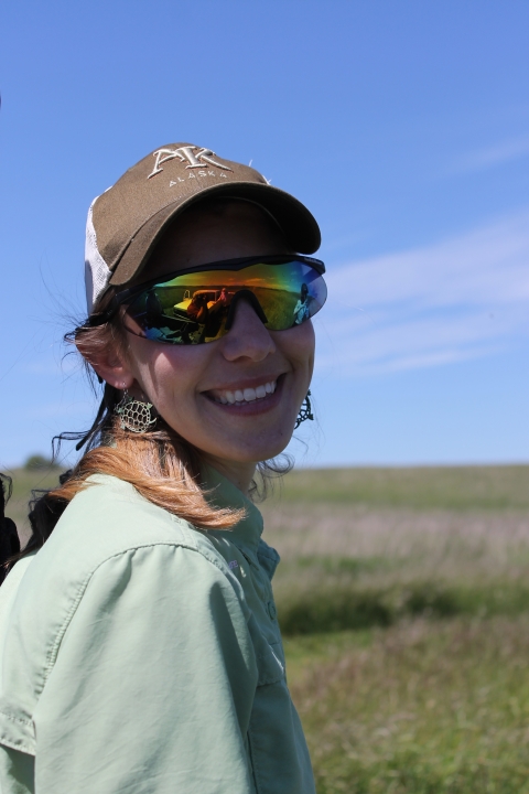 Person in hat and sunglasses smiles at camera