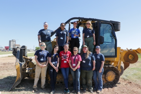 10 women on or in front of dozer pose