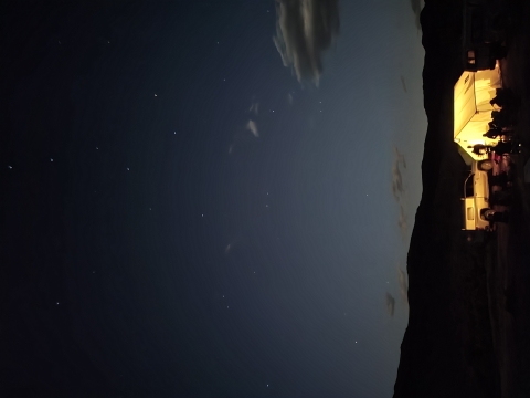 A light illuminates a small camp under the night sky.