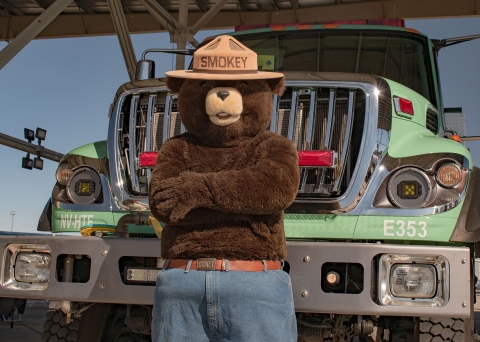 Smoket Bear standing in front of a fire truck