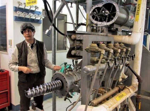 Woman standing behind a large piece of industrial machinery