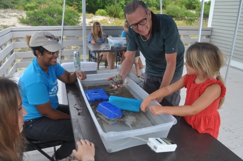 Image of visitors looking at snail during tidepool program