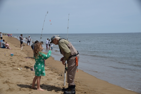 Image of adult helping youth surf fish