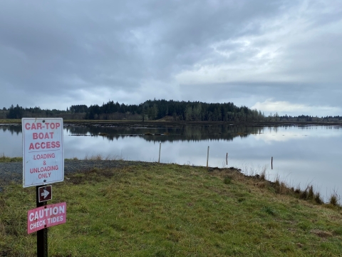 Signage indicating Car-top Boat Launch with view of the launch and tidelands in the background.