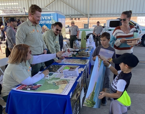 Forest Service people speaking with youngsters at an exhibit table