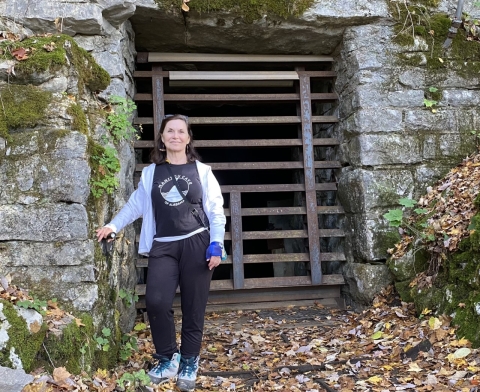 A woman in front of iron gate and cave