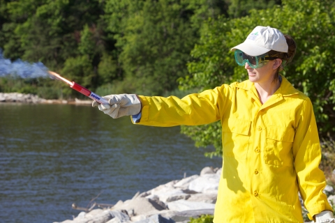 woman in yellow jacket holding flare away from body