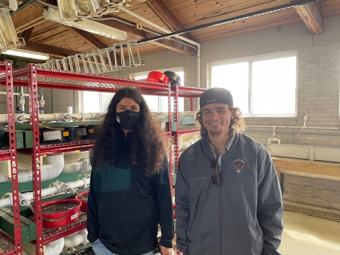 Two people stand together in a building with fisheries supplies