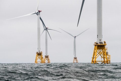 Picture of an ocean with wind turbines on the horizon.