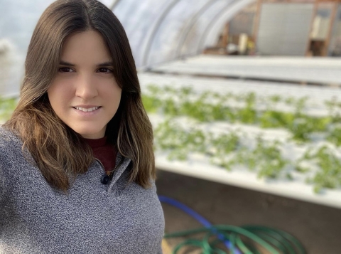 a woman takes a selfie from inside what appears to be a greenhouse