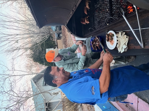 Two men cook meat on a barbeque