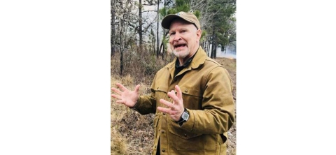 Service biologist John Hammond stand in a long leaf pine forest.