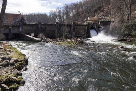 Downstream view of a dam stretching across a river, with water flowing through the right end