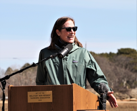 A woman speaking at a lectern outside