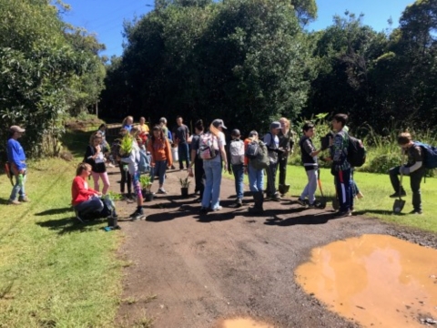 Student and volunteers stand along a dirt road. 