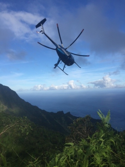 A helicopter flies above a mountain range. 