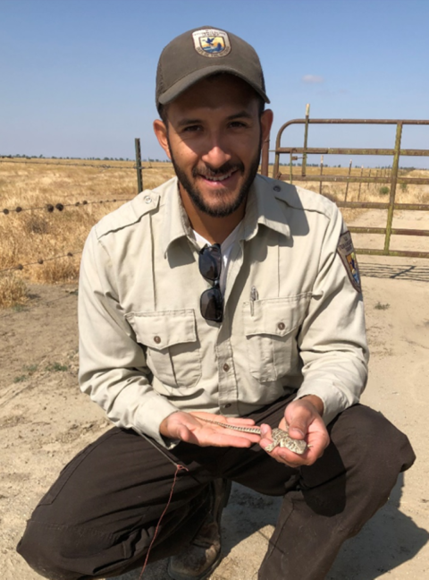 A man in a Service uniform holding a lizard in the palm of his hand