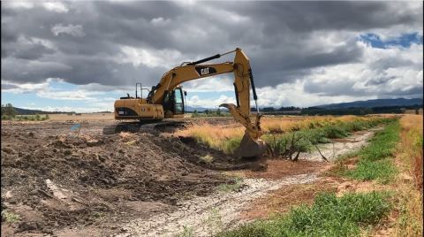 Tractor excavating a stream channel