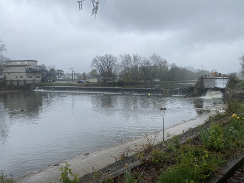 Looking upstream at the Charles Mill dam with a person fishing in front