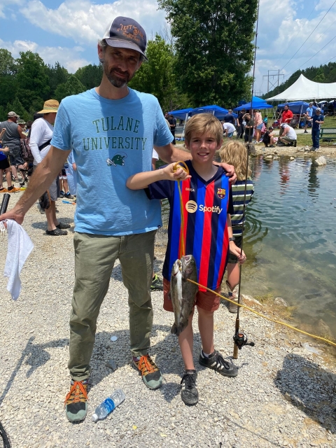 Father and son with stringer of fish beside stream