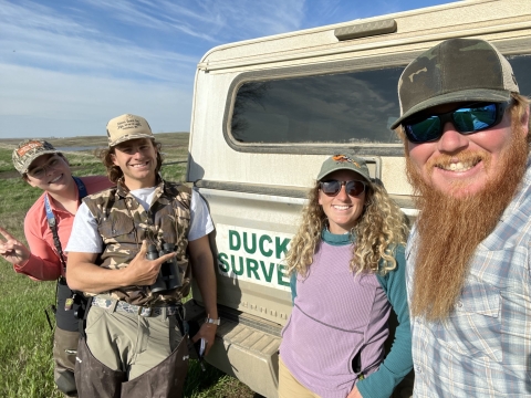 four people standing in front of a truck 